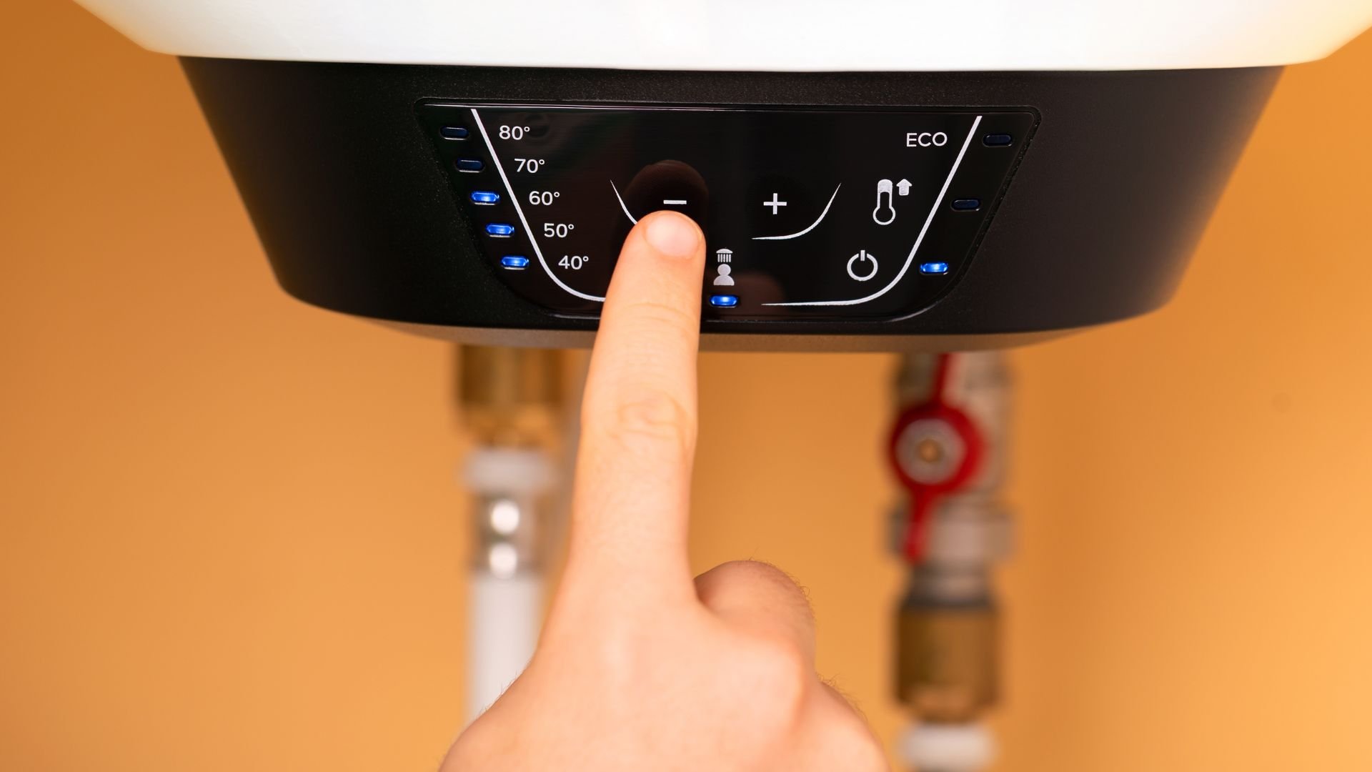 Finger adjusting temperature on digital water heater control panel