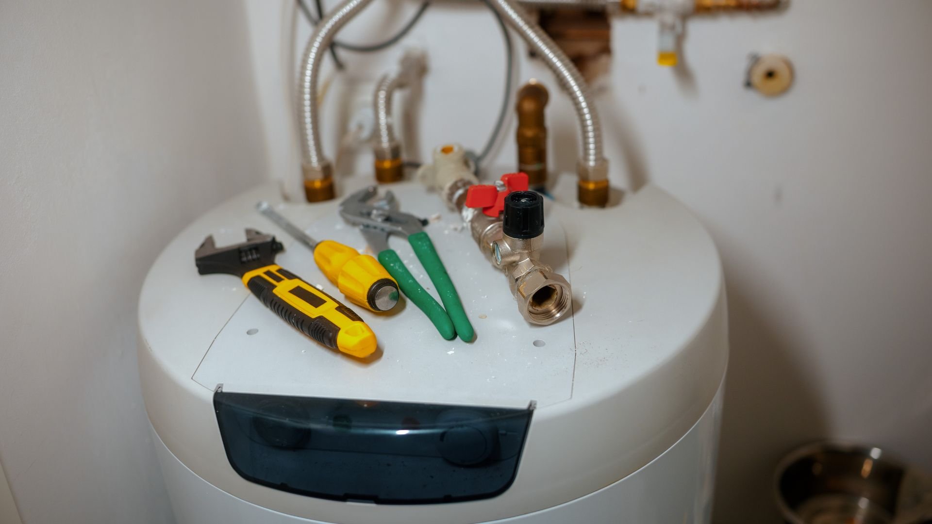 Plumbing tools and valves on top of a white water heater