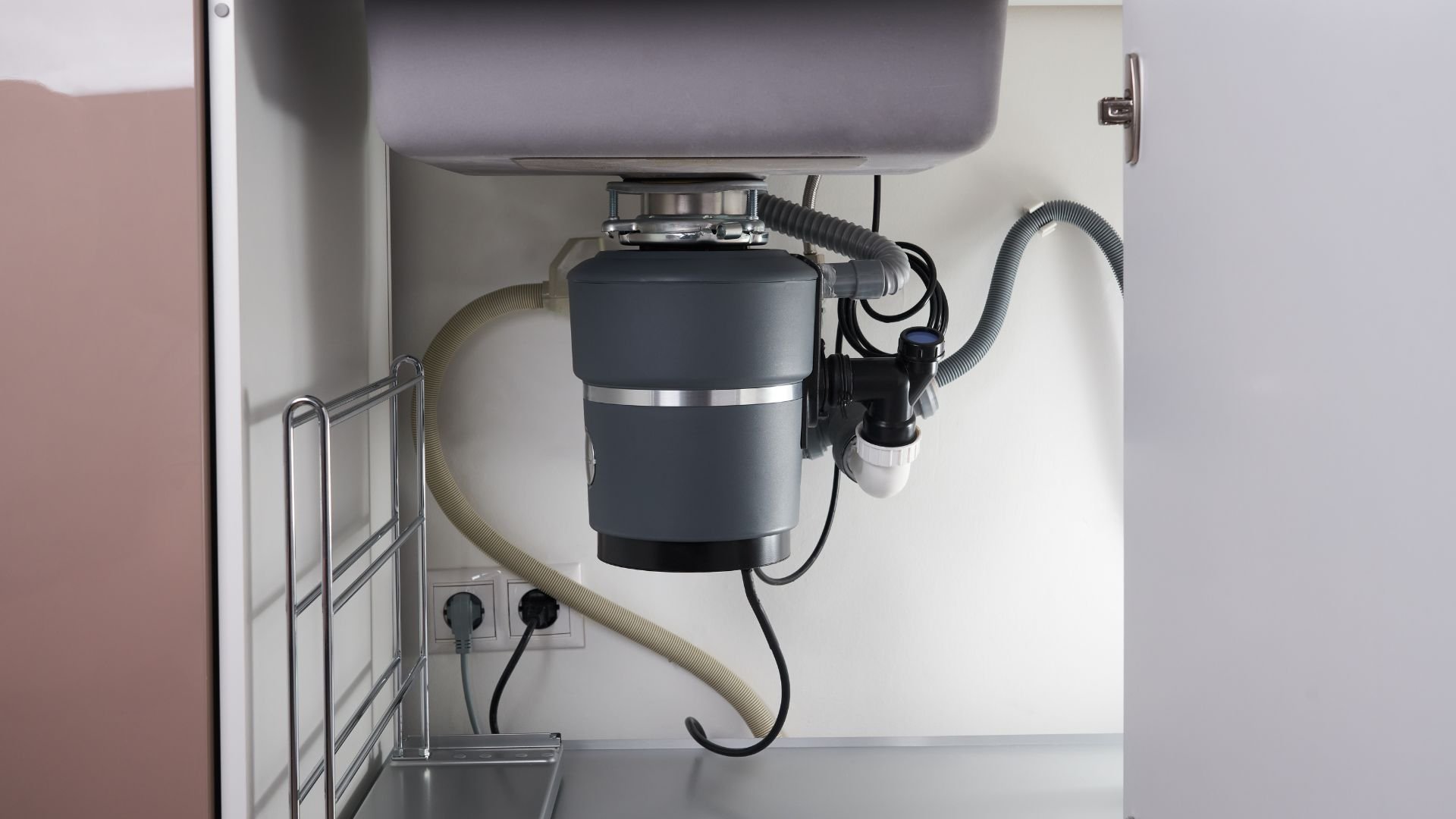Modern garbage disposal unit installed under kitchen sink with electrical connections