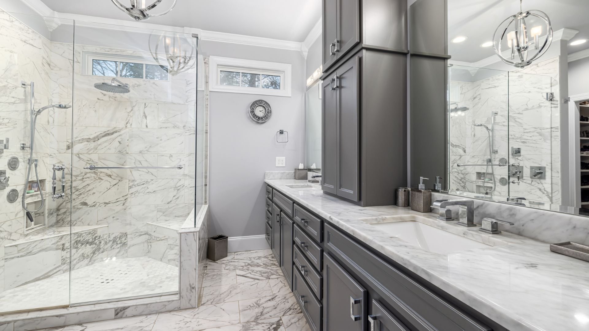 Luxurious marble bathroom with gray cabinets and glass shower