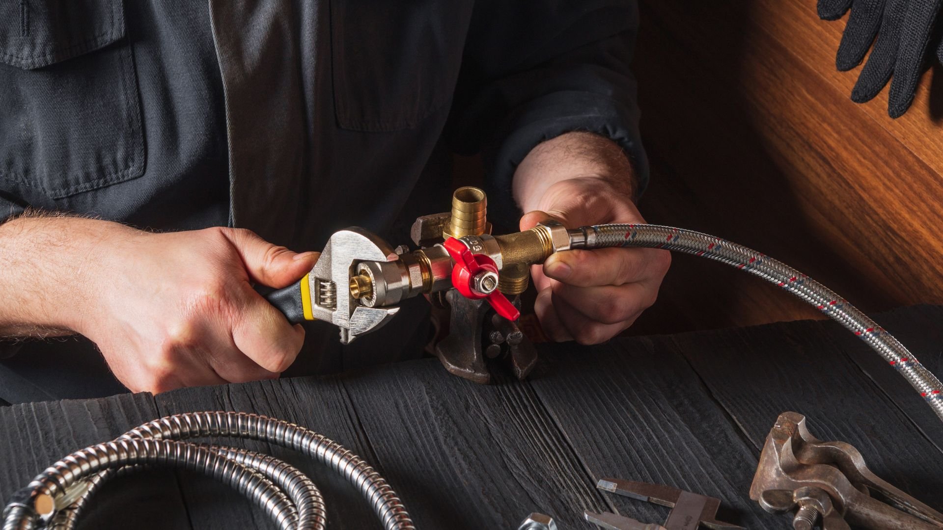 Plumber adjusting pipe connections with wrench and red valve